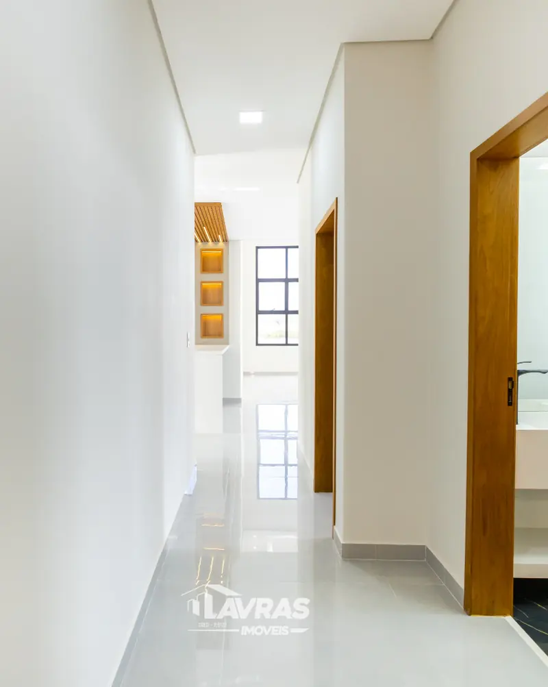 Corredor branco com piso claro e portas de madeira